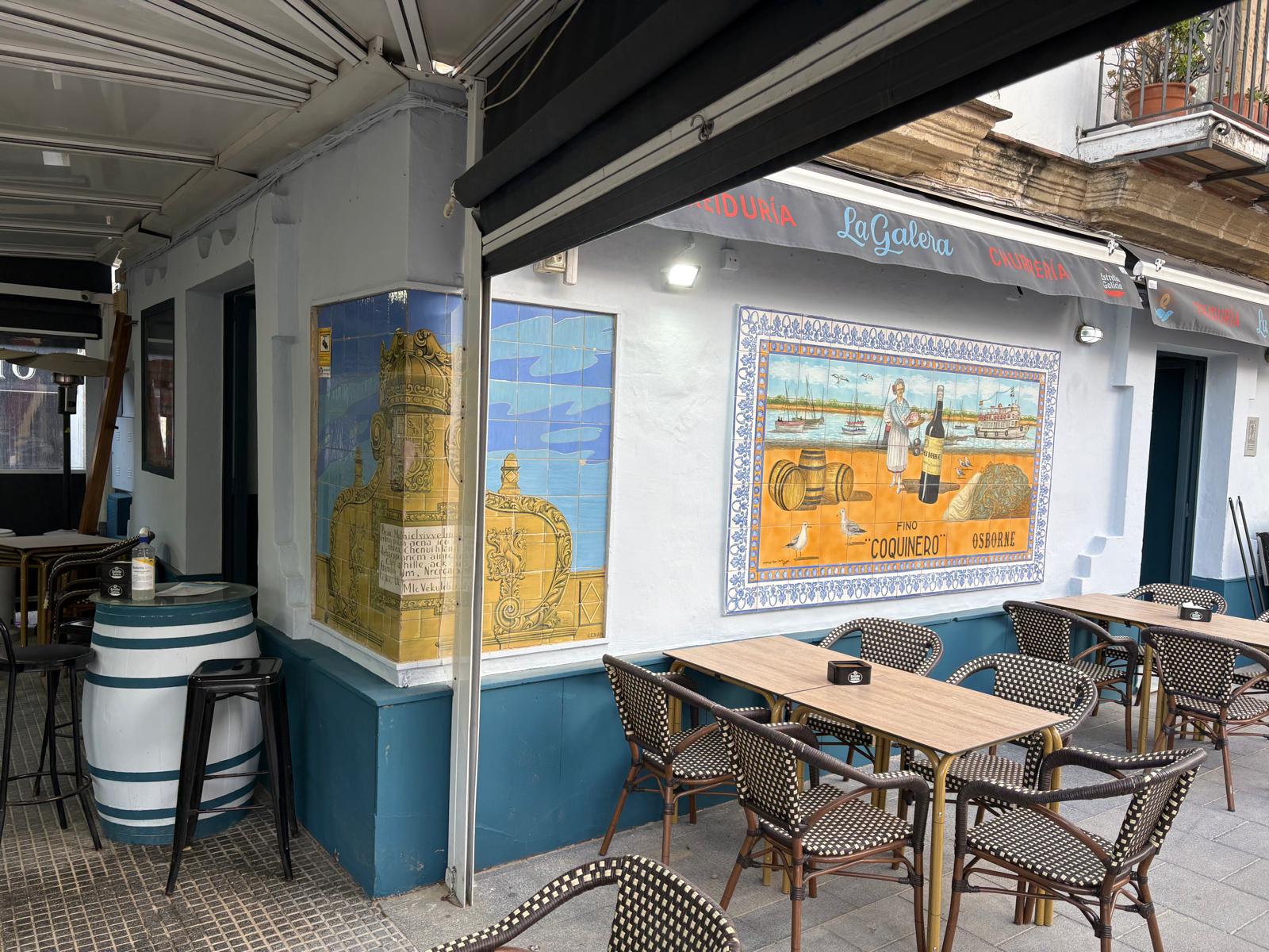 Terraza de La Galera en El Puerto de Santa María con paneles de azulejos pintados y mesas de enea.